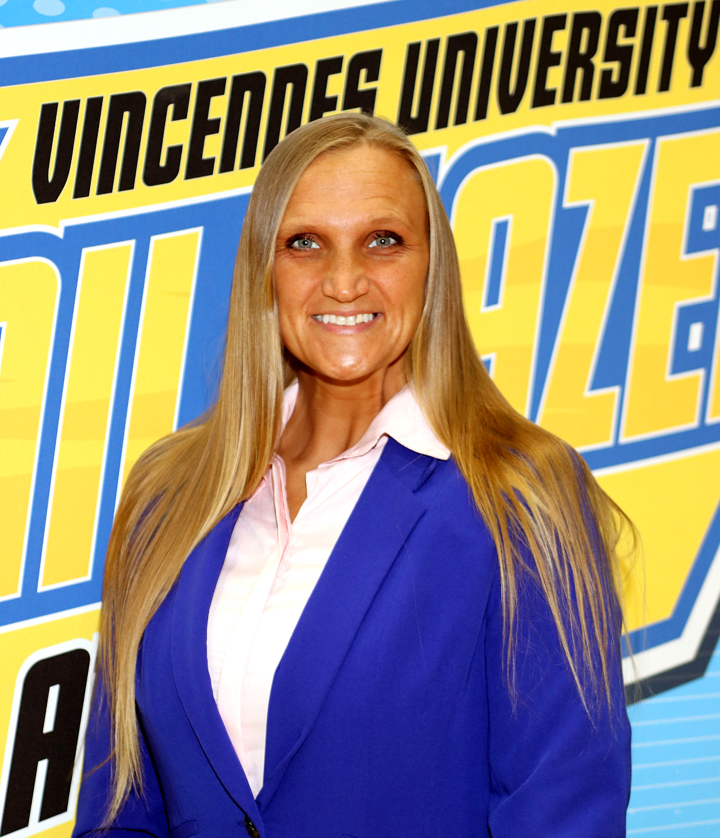 A headshot of Ingrida Hartsfield wearing professional clothing and standing with a VU Athletics step and repeat in the background.